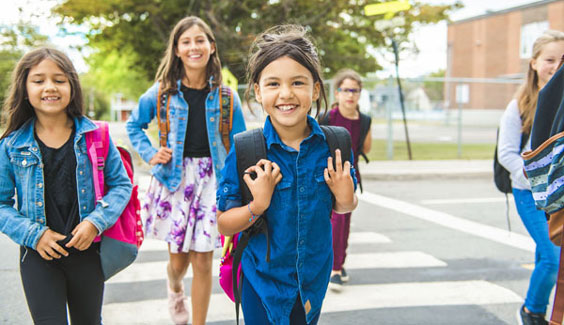 Group of students walking in crosswalk smiling